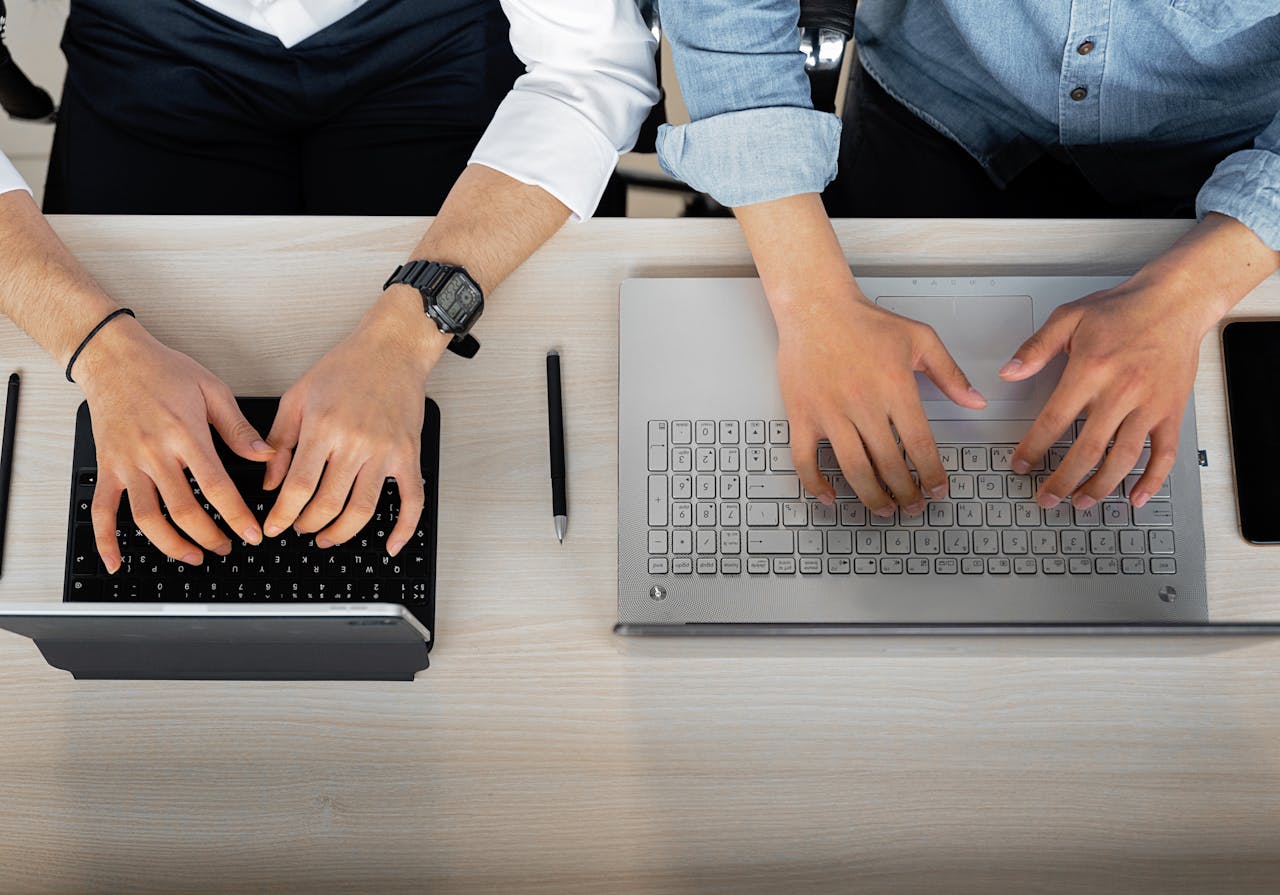 Two people working together with laptops and tablets at a modern workspace.